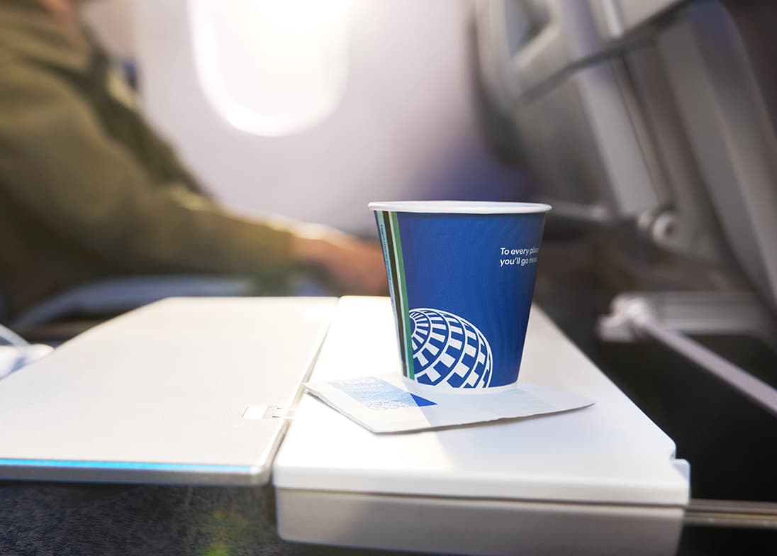 Blue paper cup on plane tray table